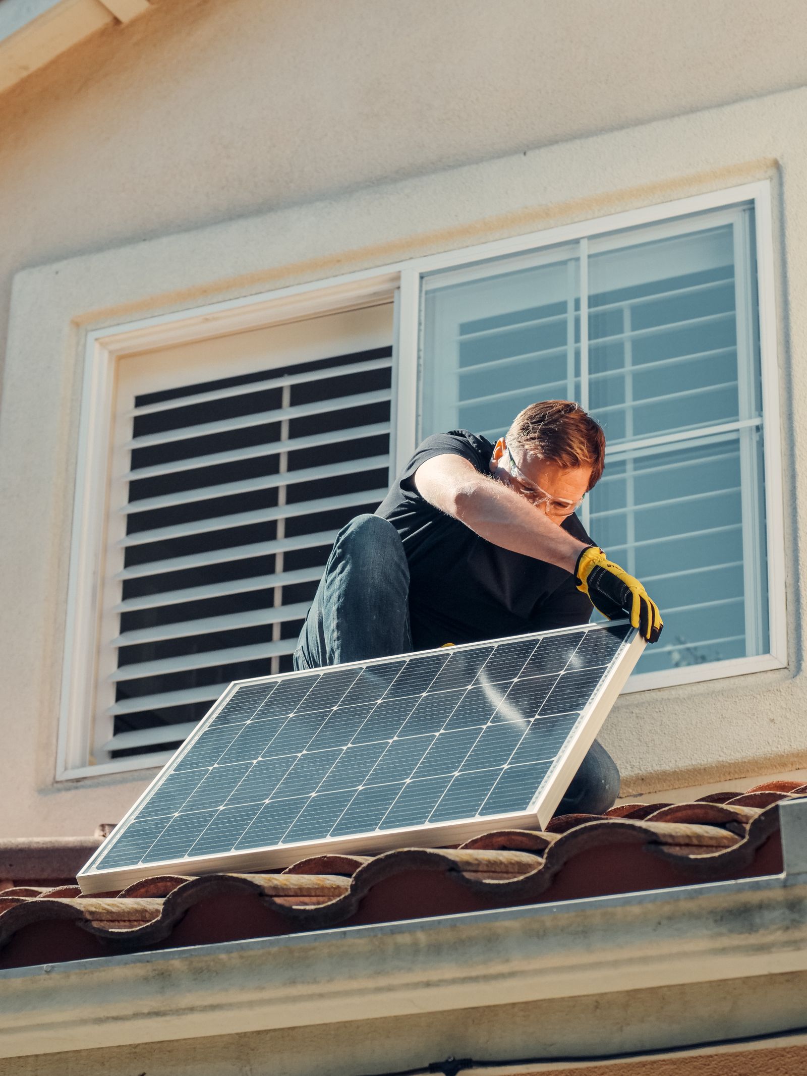 Monteur setzt ein Photovoltaikmodul auf ein Ziegeldach